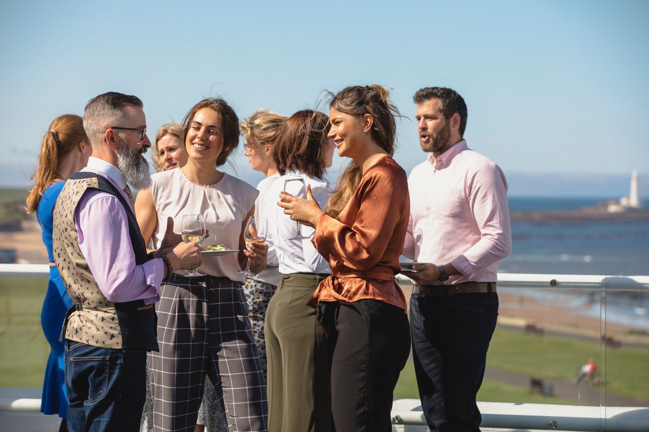 Colleagues enjoying drinks on windy roof terrace at corporate event